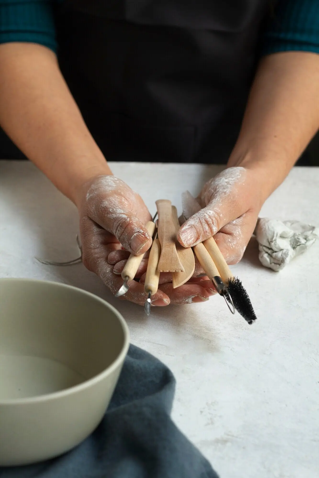 Ansicht von oben: Hände halten Töpferwerkzeuge.