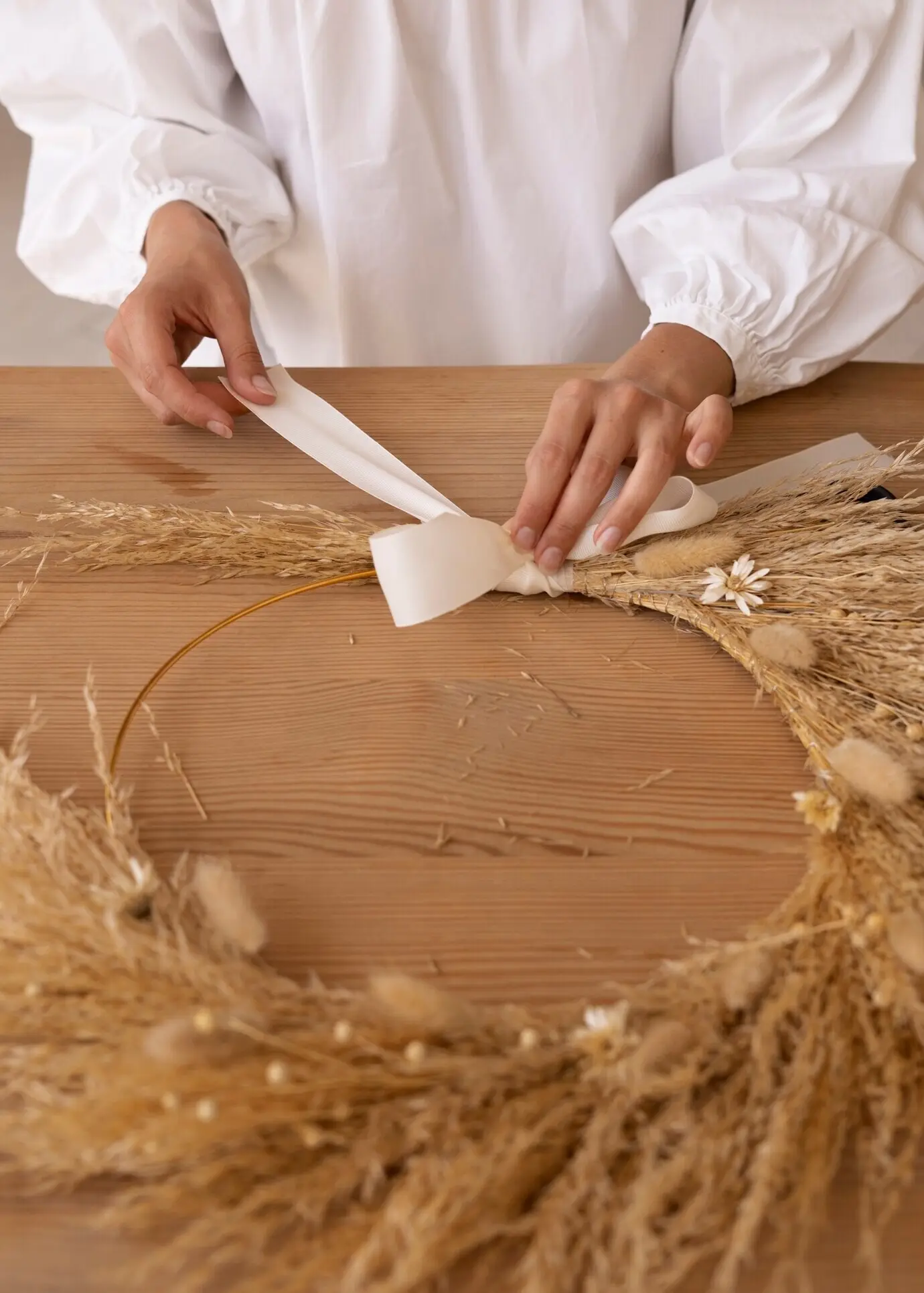 Eine Frau stellt ihr eigenes Arrangement aus getrockneten Blumen zusammen.
